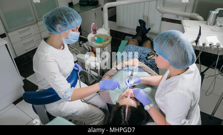 Frau beim Zahnarzt Klinik erhält der zahnmedizinischen Behandlung ein Loch in einen Zahn zu füllen. Zahnersatz und Verbundmaterial Polymerisation mit UV-Licht und Laser. Stockfoto