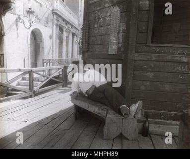 Ein Mann schläft auf einer Bank in einer Seitenstraße, Venedig, Italien Stockfoto