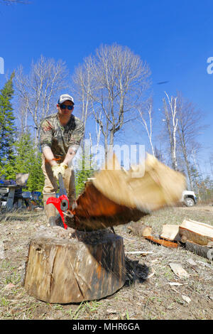 Ein Mann, der mit einer Axt Brennholz spaltet. Stockfoto