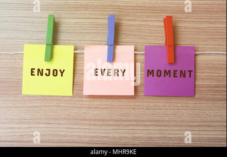 Genießen jeden Augenblick Inspirational Anführungsstrich auf Notes hängt von wäscheklammern Stockfoto