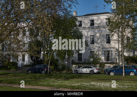 Autos vor Regency Häuser im Schatten von Bäumen geparkt, Cheltenham Spa, Gloucestershire. Stockfoto