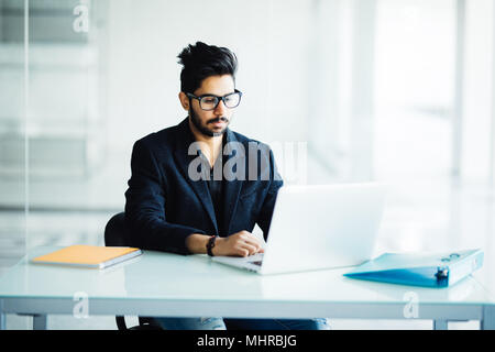 Nachdenkliche junge internationale männlichen Studenten, die Konzeption für die Kursphase vorbereiten, um Bericht über die Lektion beim Sitzen am Schreibtisch ohne Stockfoto