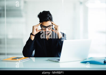 Closeup Portrait eines langen Kerl tief in Gedanken, während Sie an seinem Laptop, Studium ernst, auf eine Stadt und Natur Hintergrund in seinem Haus isoliert oder Stockfoto