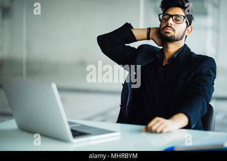 Müde und besorgt, indische Geschäftsmann am Arbeitsplatz im Büro Stockfoto