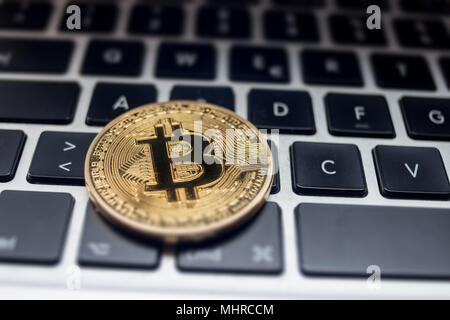 Physische Bitcoin auf Laptop Tastatur platziert Stockfoto