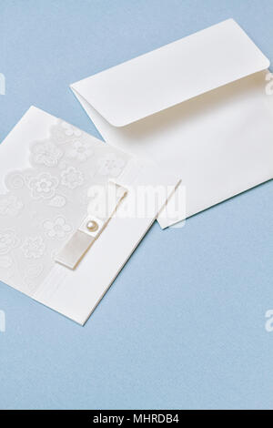 Weiß hochzeit einladung mit Blumen spitze Abbildung und White Ribbon auf hellblauem Papier Hintergrund. Vertikale erschossen. Süße und schöne Elemente. Stockfoto