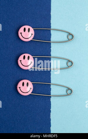 Kunststoff Kopf metall Sicherheitsnadeln in Papier festgesteckt. Rosa Lächeln emoticon Safety Pin. Nett und lustig bunte Emoticons. Stockfoto