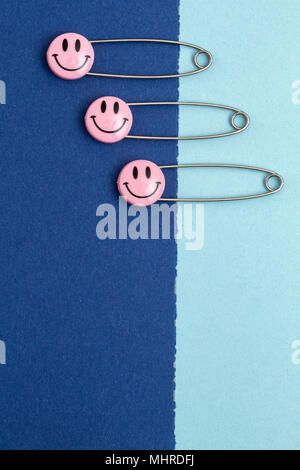 Kunststoff Kopf metall Sicherheitsnadeln in Papier festgesteckt. Rosa Lächeln emoticon Safety Pin. Nett und lustig bunte Emoticons. Stockfoto