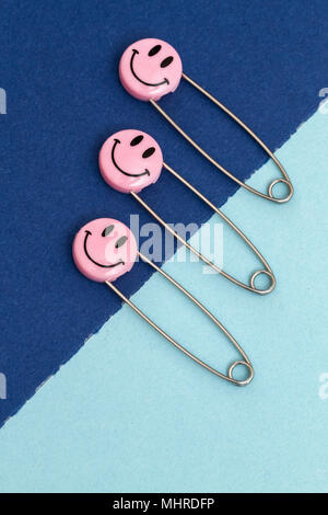 Kunststoff Kopf metall Sicherheitsnadeln in Papier festgesteckt. Rosa Lächeln emoticon Safety Pin. Nett und lustig bunte Emoticons. Stockfoto