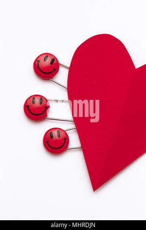 Kunststoff Kopf metall Sicherheitsnadeln in Herzform Papier festgesteckt. Rot Lächeln emoticon Safety Pin. Nett und lustig bunte Emoticons. Stockfoto