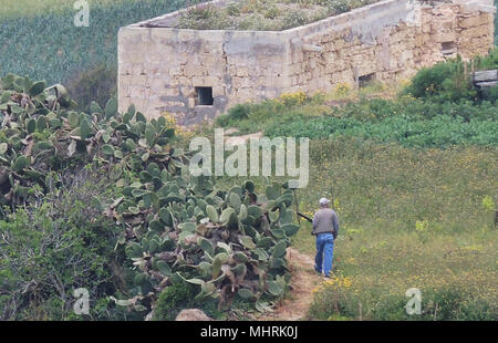 12 April 2018, Malta, Rabat: ein Jäger schlängelt sich durch die Hügellandschaft. Malta ist das einzige Land in der Europäischen Union, mit der Vogeljagd im Frühling. In diesem Jahr jedoch die Jagd auf Wachteln nur eingeschränkt. Foto: Lena Klimkeit/dpa Stockfoto