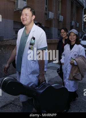 (180503) - Peking, Mai 3, 2018 (Xinhua) - Doktor Zheng Zhibo (L), Mitglied der "Xieyun' Orchestra, kehrt zu seinem Schlafsaal in Peking Union Medical College Hospital (PUMCH) in Peking, der Hauptstadt von China, 23. April 2018. 2015, PUMCH Ärzte und Peking Union Medical College Studenten gestartet Die "Xieyun' Orchester. Jeden Monat, Mitglieder von 'Xieyun' würde freiwillig ein oder zwei musikalische Darbietungen für Patienten, ihre Familien und andere medizinische Arbeiter. Das Orchester wurde weitgehend von seinem Publikum für seine Leistungen und Anliegen der Mitglieder und die Liebe zu den Patienten geschätzt. (Xin Stockfoto