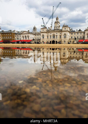 London. UK vom 3. Mai 2018 - Reflexion von Regierungsgebäuden und baukräne an einem sonnigen Tag in einer Pfütze von Wasser in Horse Guards durch vor kurzem Starkregen Kredit verursacht: Roamwithrakhee/Alamy leben Nachrichten Stockfoto