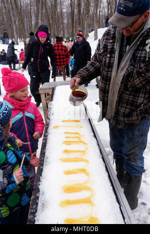 Kinder essen Ahornsirup taffy auf Eis zu einem Sugar shack in Québec, Kanada gegossen Stockfoto