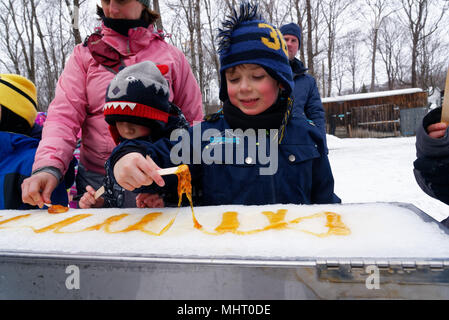 Kinder essen Ahornsirup taffy auf Eis zu einem Sugar shack in Québec, Kanada gegossen Stockfoto