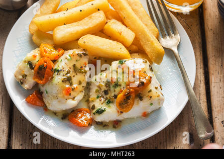 Kabeljaufilets mit Cherry Tomaten, weißen Wein & Basilikum Dressing mit Pommes frites serviert. Stockfoto