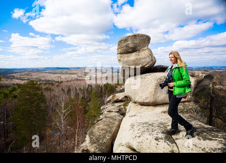 Junge Frau mit Kamera auf der Klippe. Stockfoto