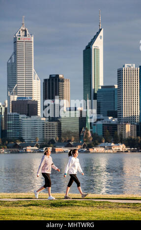 Zwei Frauen gehen neben dem Swan River in Perth Perth City in der Ferne Stockfoto