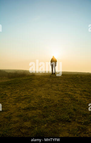 Rückansicht eines männlichen Figur stehend auf dem Feld bei Sonnenuntergang Stockfoto