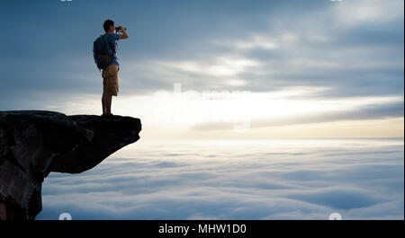 Der Mann im mittleren Alter auf der Klippe mit Blick auf Stockfoto