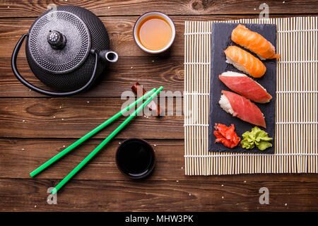 Sushi Set serviert auf grauem Stein Schiefer mit Sojasoße, grau Teekanne und Tasse Tee Stockfoto