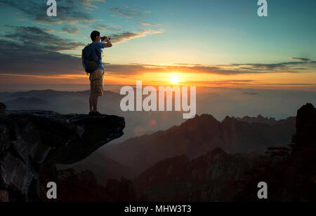 Der Mann im mittleren Alter auf der Klippe mit Blick auf Stockfoto