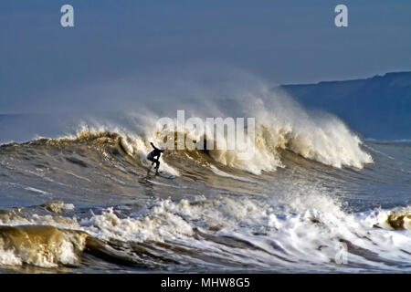 Ein einsamer Surfer reitet eine beeindruckende ankommenden Welle in der Scarborough South Bay. Stockfoto