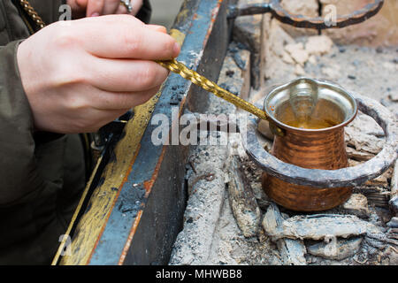 Frau kocht türkischen Kaffee in Grill. angenehm und reichlich schaumigen Stockfoto