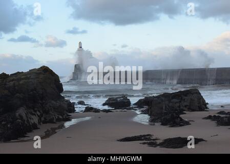 Wellen brechen über Aberdeen Wellenbrecher und um Leuchtturm im Sturm. Stockfoto