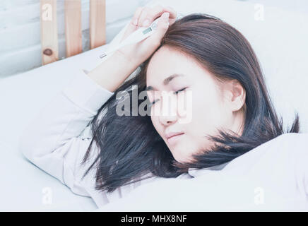 Asiatische Frau krank Schlafen auf weißem Kissen auf dem Bett im Schlafzimmer in der Ferienwohnung. Stockfoto