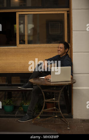 Geschäftsmann mit Laptop im Straßencafé sitzen Stockfoto