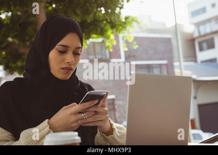 Hijab Frau mit Handy an Cafe Stockfoto