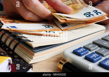 Mann zählen von Euro-banknoten. Schreibtisch mit Rechner, Hauptbuch und Euro. Stockfoto