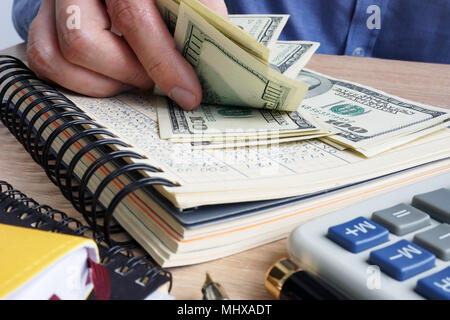 Mann zählen Dollarscheine. Schreibtisch mit Rechner, Hauptbuch und Dollar. Stockfoto