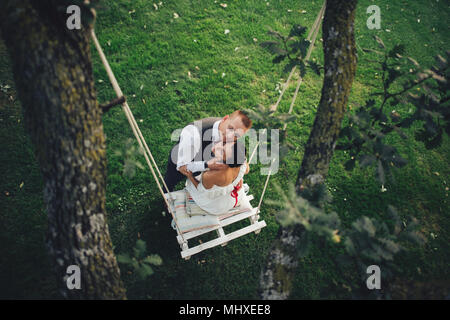 Schöne Braut Bräutigam umarmt von hinten stehend auf dem Pass zwischen den Bäumen Stockfoto