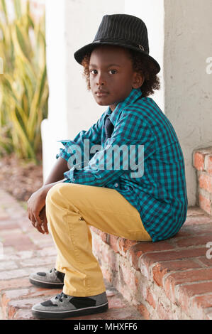 Portrait von Jungen, Sitzen im Freien, das Tragen von Fedora Stockfoto