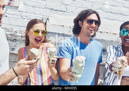 Junge Frauen und Männer halten schmelzen Eistüten, Lachen Stockfoto