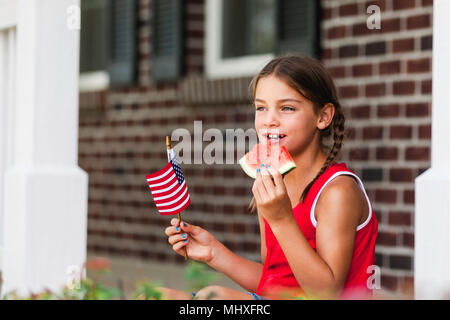 Junge Mädchen im Freien, kleine amerikanische Flagge, essen ein Stück Wassermelone Stockfoto