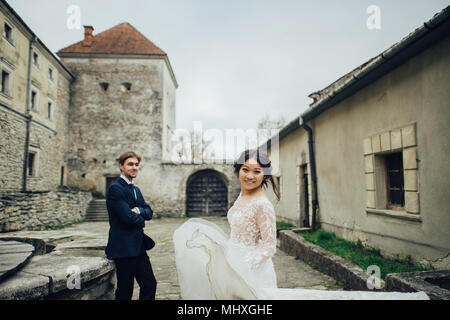 Glückliches Paar der Jungvermählten bei Sonnenuntergang mit Schloss wand hintergrund küssen Stockfoto