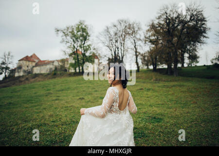 Asiatische Braut in eleganten Hochzeitskleid laufen Outdoor Stockfoto