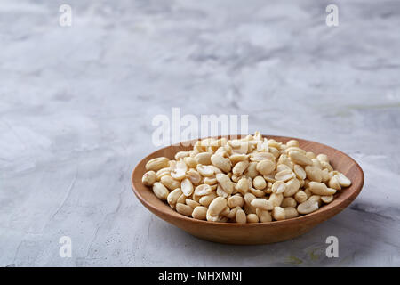 Stapel von peelled Erdnüsse auf weiße strukturierte Hintergrund, Hintergrund, Ansicht von oben, Nahaufnahme, selektiven Fokus. Organische nahrhafte Zutat. Gourmet Stockfoto