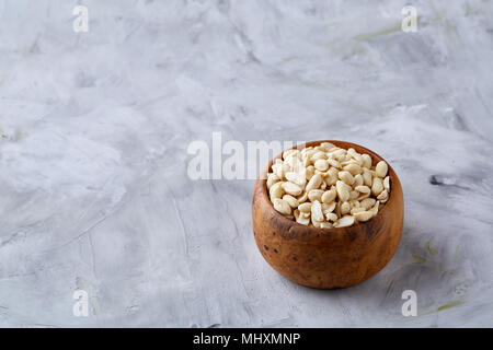 Stapel von peelled Erdnüsse auf weiße strukturierte Hintergrund, Hintergrund, Ansicht von oben, Nahaufnahme, selektiven Fokus. Organische nahrhafte Zutat. Gourmet Stockfoto