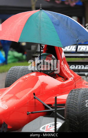 Ein Rennfahrer Unterstände unter einem Sonnenschirm an einem sehr nassen hillclimb Treffen in Prescott, Gloucestershire, England, UK. Stockfoto