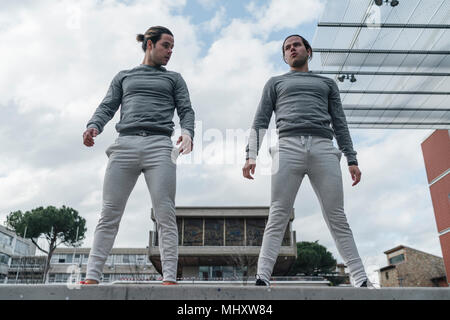 Jungen Erwachsenen männlichen Zwillingen Ausbildung, stehend an der Wand, Low Angle View Stockfoto