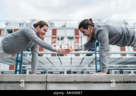 Jungen Erwachsenen männlichen Zwillingen Ausbildung, einer bewaffneten Push-ups Stockfoto