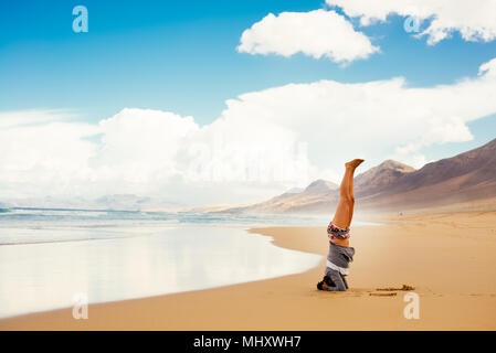 Frau tun Kopfstand am Strand, Corralejo, Fuerteventura, Kanarische Inseln Stockfoto