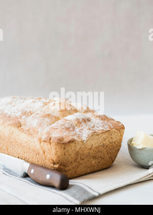 Frisch gebackenen Laib Vollkornbrot mit Messer und Butter Stockfoto