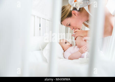 Die Mutter küssen Baby Füße im Kinderbett Stockfoto