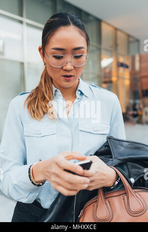 Portrait der Unternehmerin im Freien, mit Smartphone, nachdenklichen Ausdruck Stockfoto
