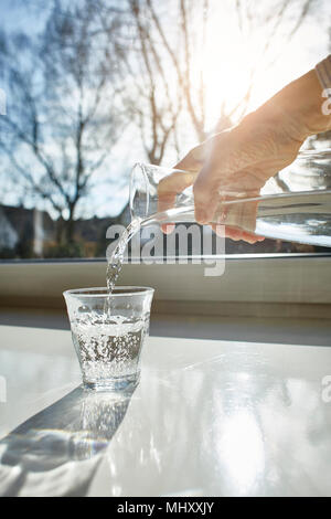 Ältere Frau gießen Glas Wasser, close-up Stockfoto